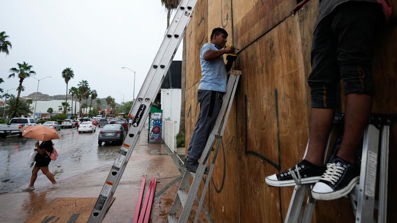 Employees cover the windows of a souvenirs store with wood in preparation for the arrival of...